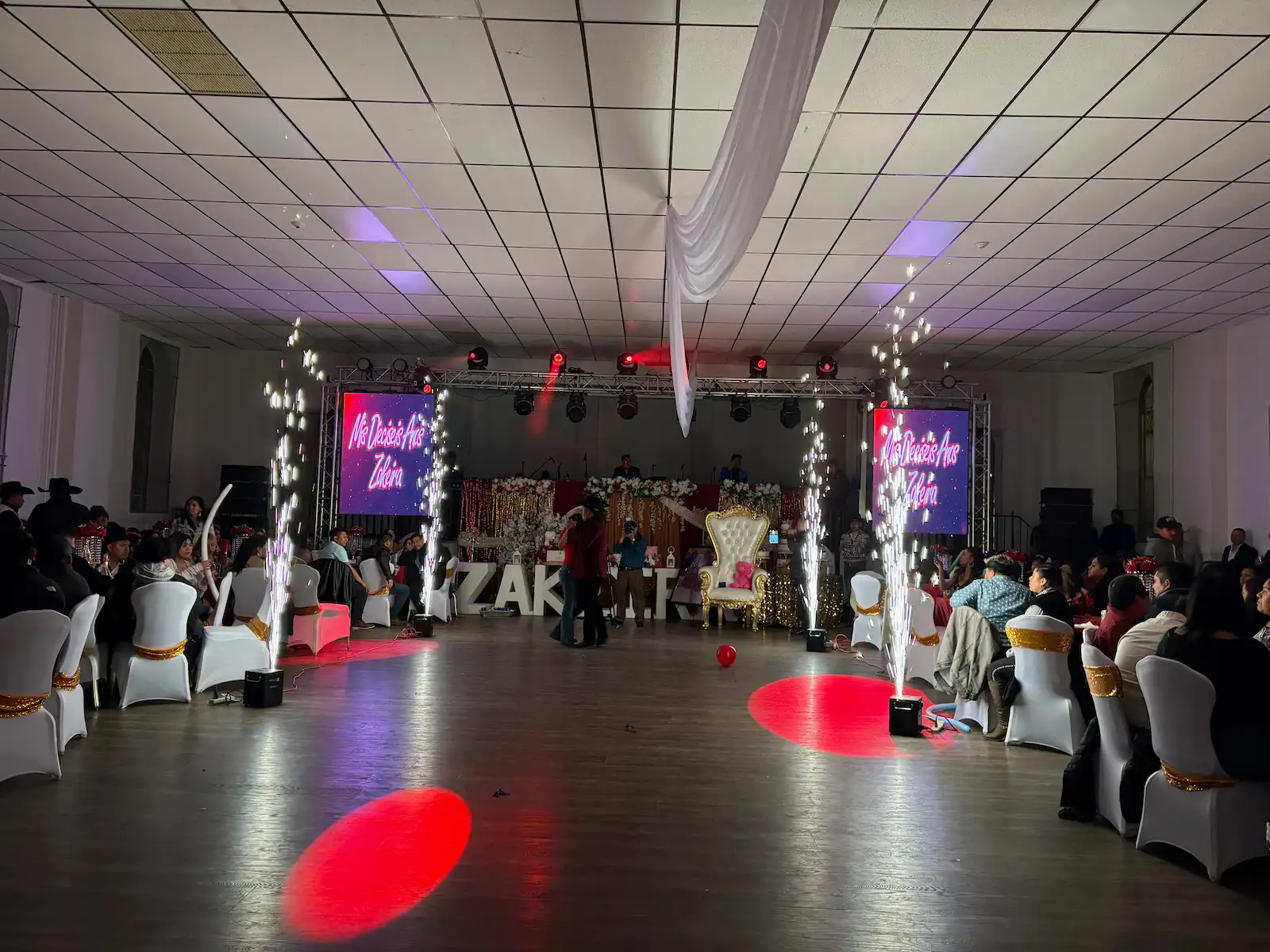 Indoor corporate event with stage lighting, LED screens, and seated guests