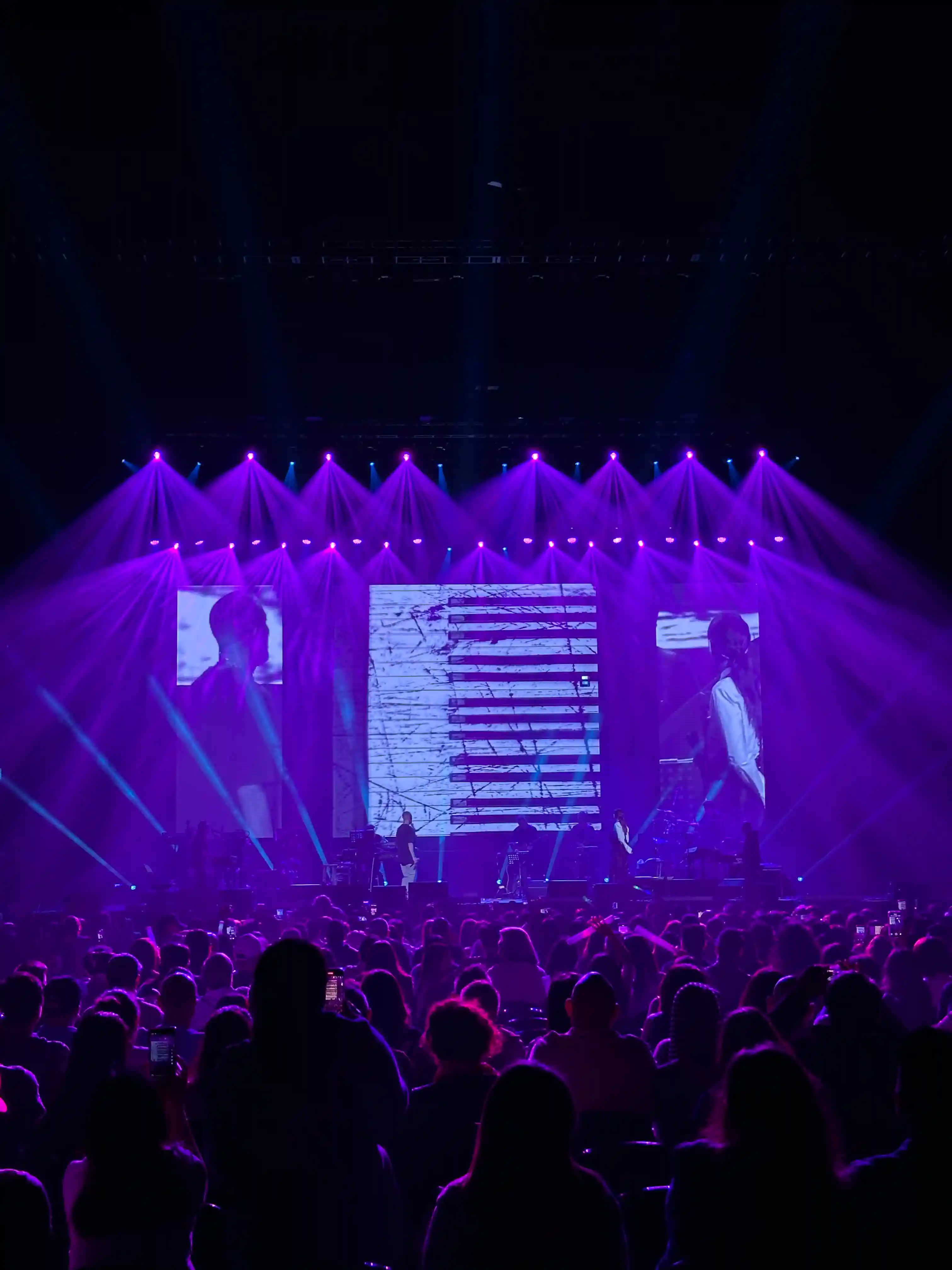 Live event with LED screen visuals and purple lighting over audience crowd